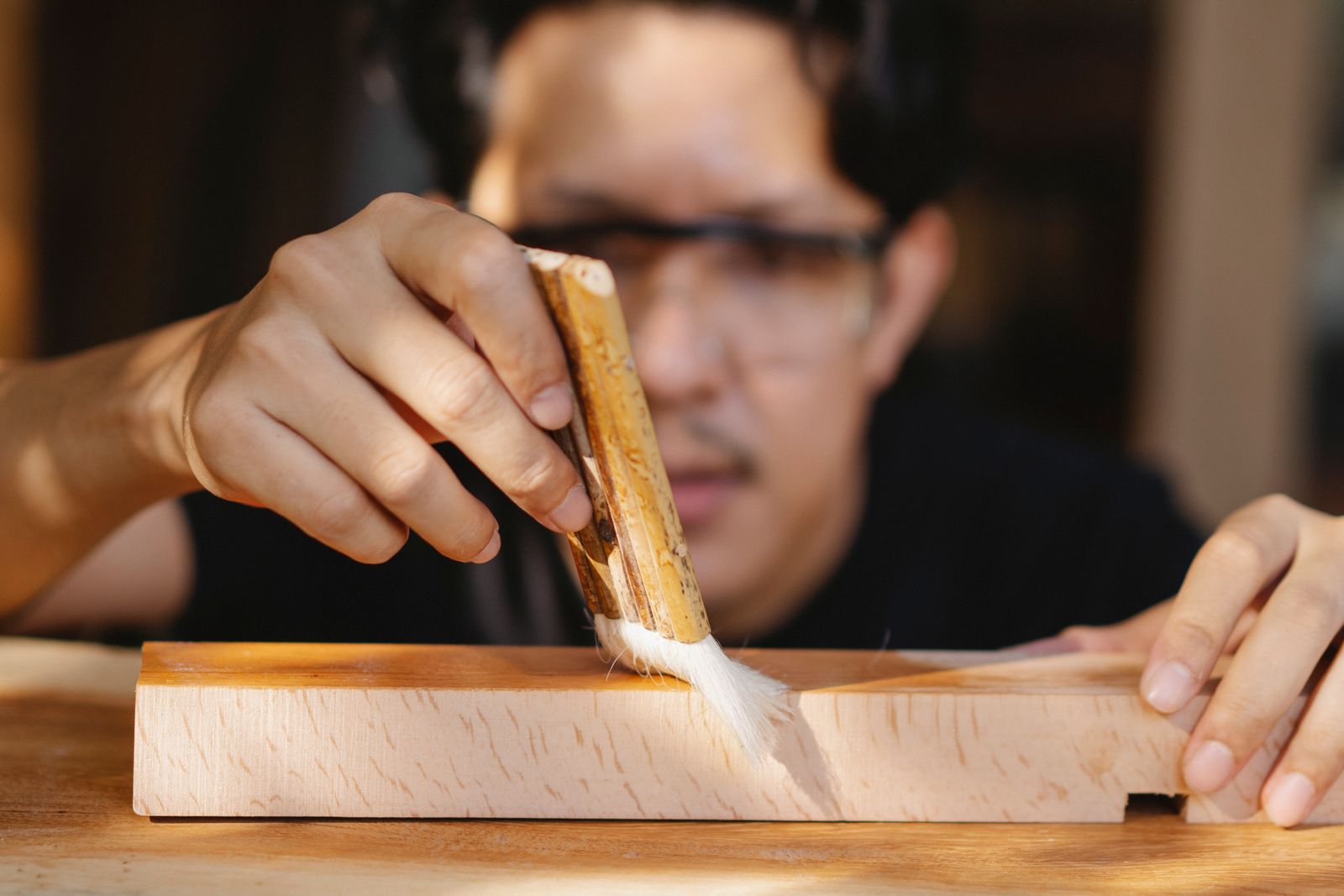 Artisan appliquant du vernis sur une pièce de bois dans son atelier